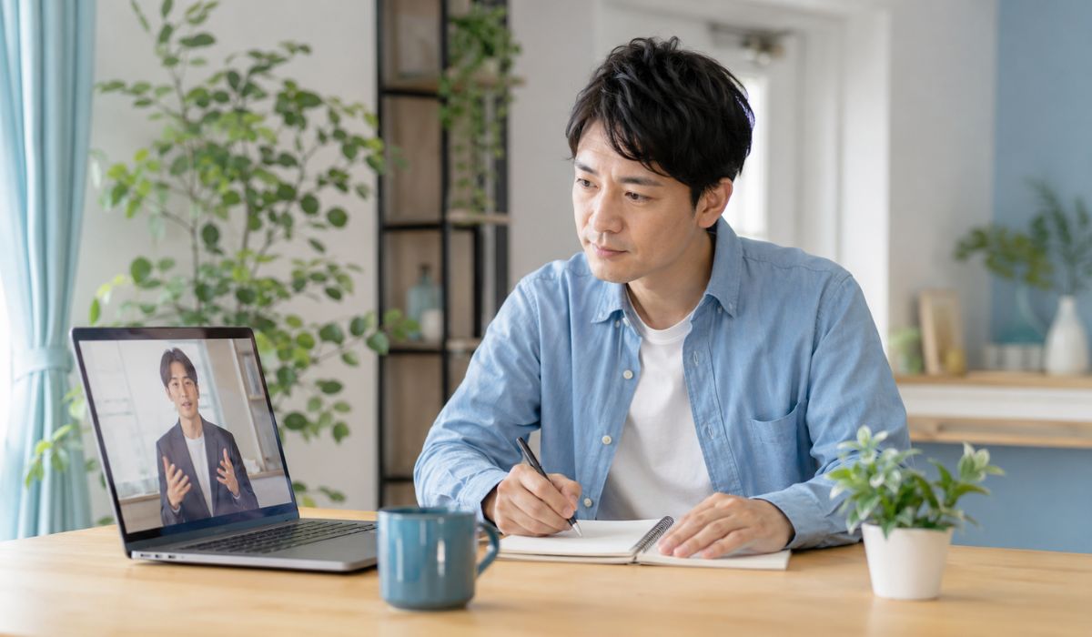 自分に必要な英語コーチを選ぶためにオンライン説明を視聴しながらメモを取る日本人男性