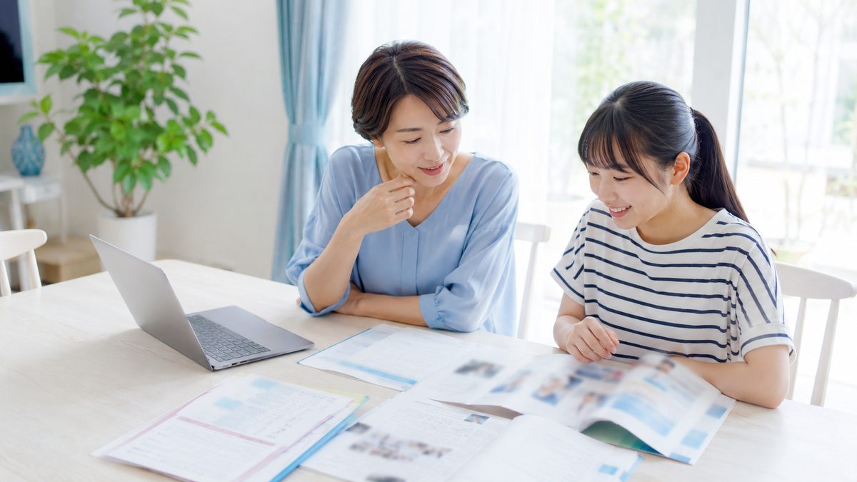 英検が優遇される大学一覧を保護者と一緒に調べる日本人の女子高校生