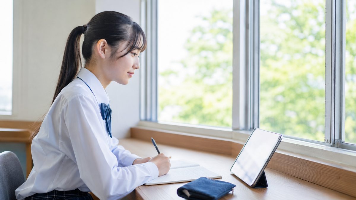 英検が使える大学の全体像をタブレットで確認する日本人の女子高校生
