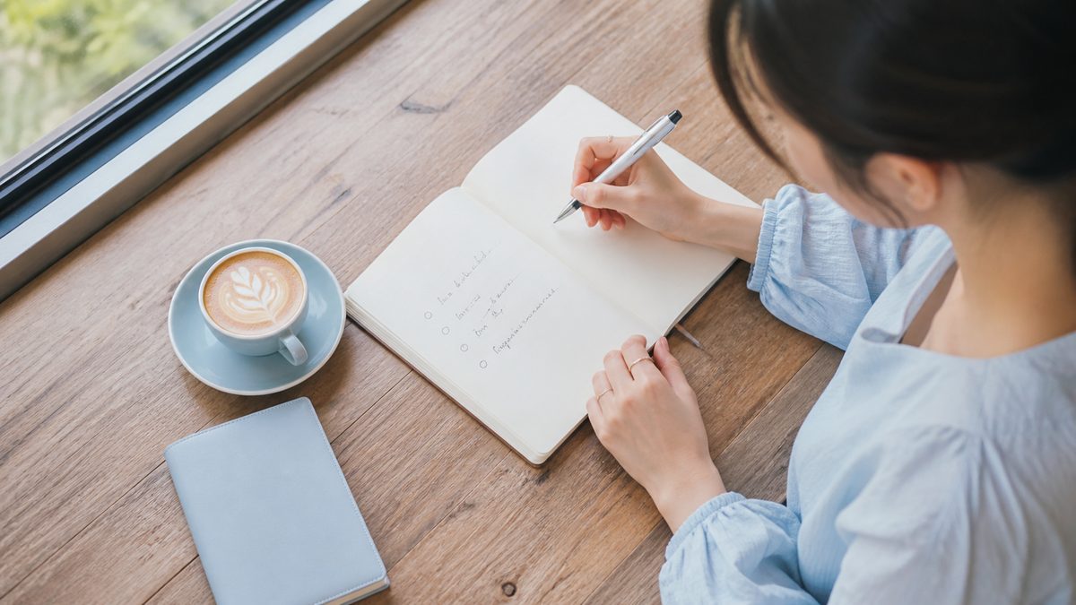 英語が話せない社会人が自分の課題を切り分けるため、カフェでノートに3つの項目を書き出して整理している手元