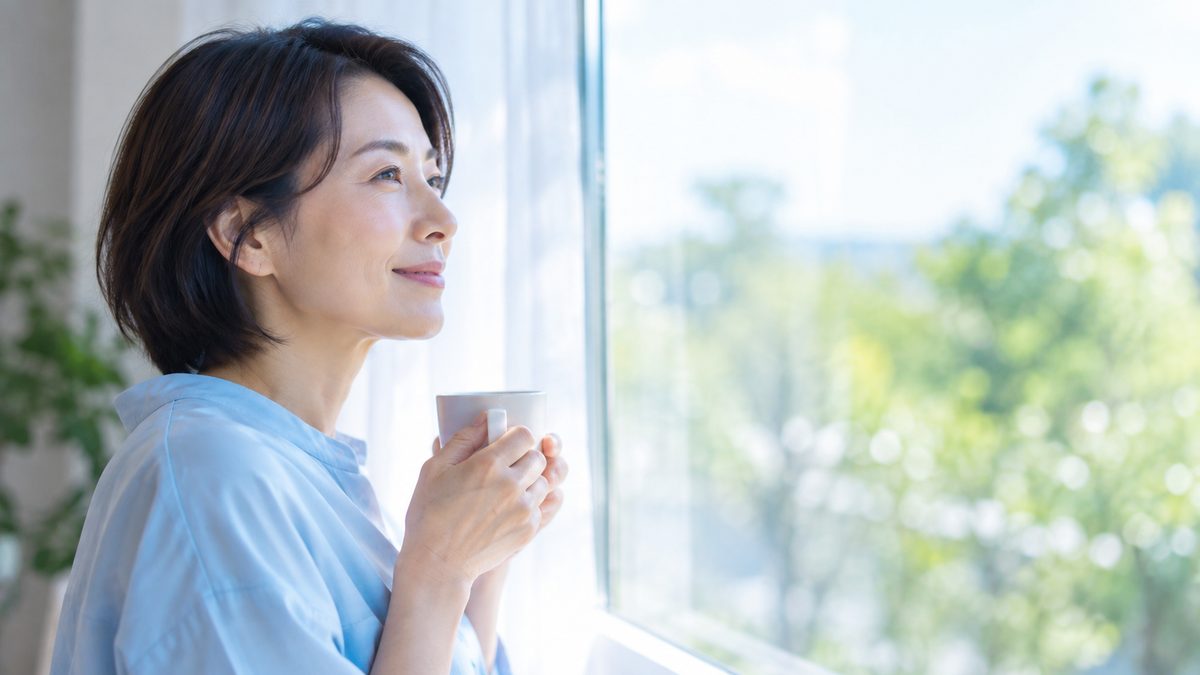 英語コーチングが意味ないと言われる理由を落ち着いて考えるため、自宅の窓辺でコーヒーを手に次の一歩を思い描く女性