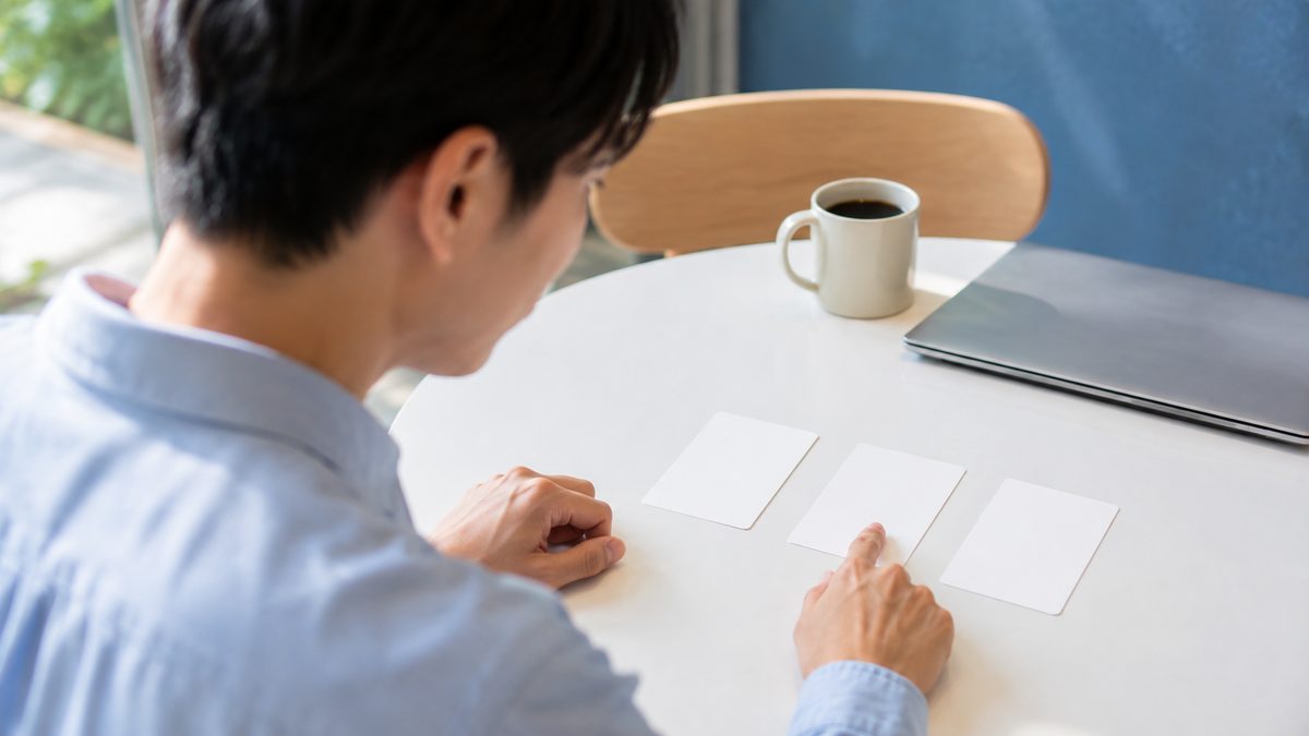 外資系転職で英語力が基準に届かないときの選択肢を、カードを並べて比較検討する20代の社会人男性