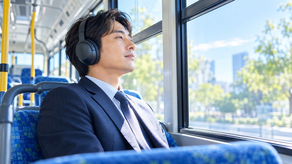 ノイズキャンセリングヘッドホンで音量を抑え、騒がしい通勤中のスキマ時間でも英語学習に集中する社会人