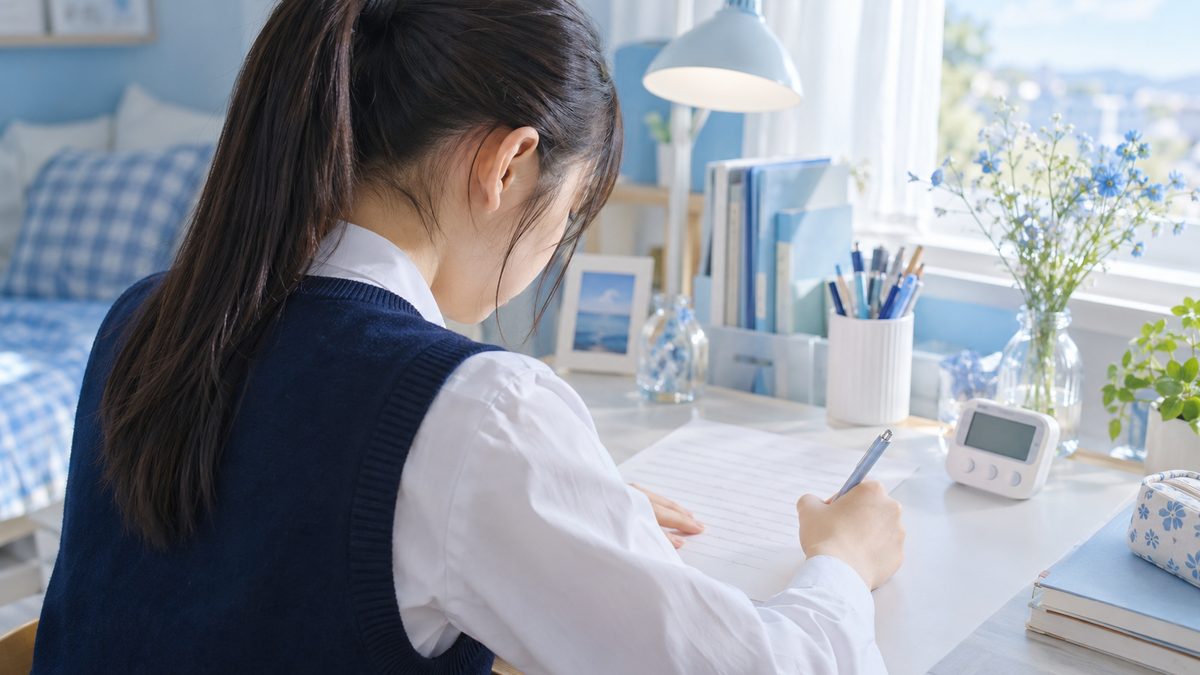 デジタルタイマーで20分を測りながら英検準1級の要約を書き進める女子高校生