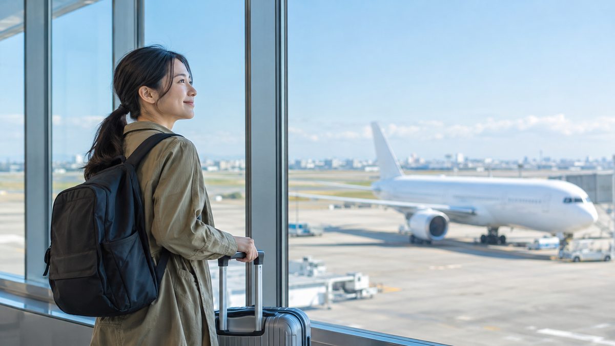ワーホリの英語準備を終え、空港の窓際で飛行機を眺めながら前向きな表情で出発を待つ日本人女性